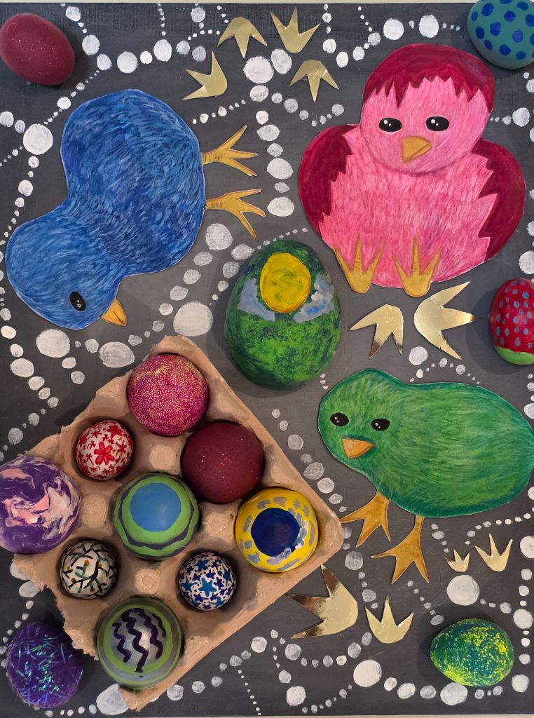 Mixed-media piece: a cardboard egg carton with fifteen hand-decorated eggs, one painted as the Earth, surrounded by cut-out chick shapes on a dark ground painted with dotted patterns.